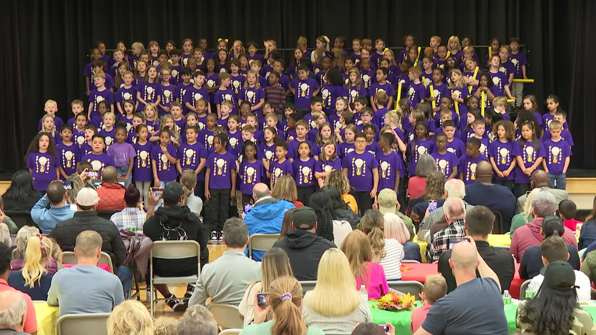 A big group of young kids on stage singing