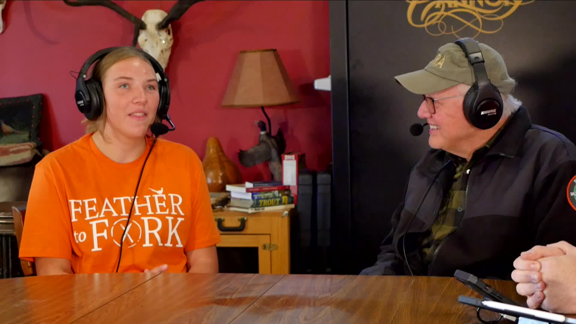 Host of podcast talking to guest with Feather to Fork on shirt