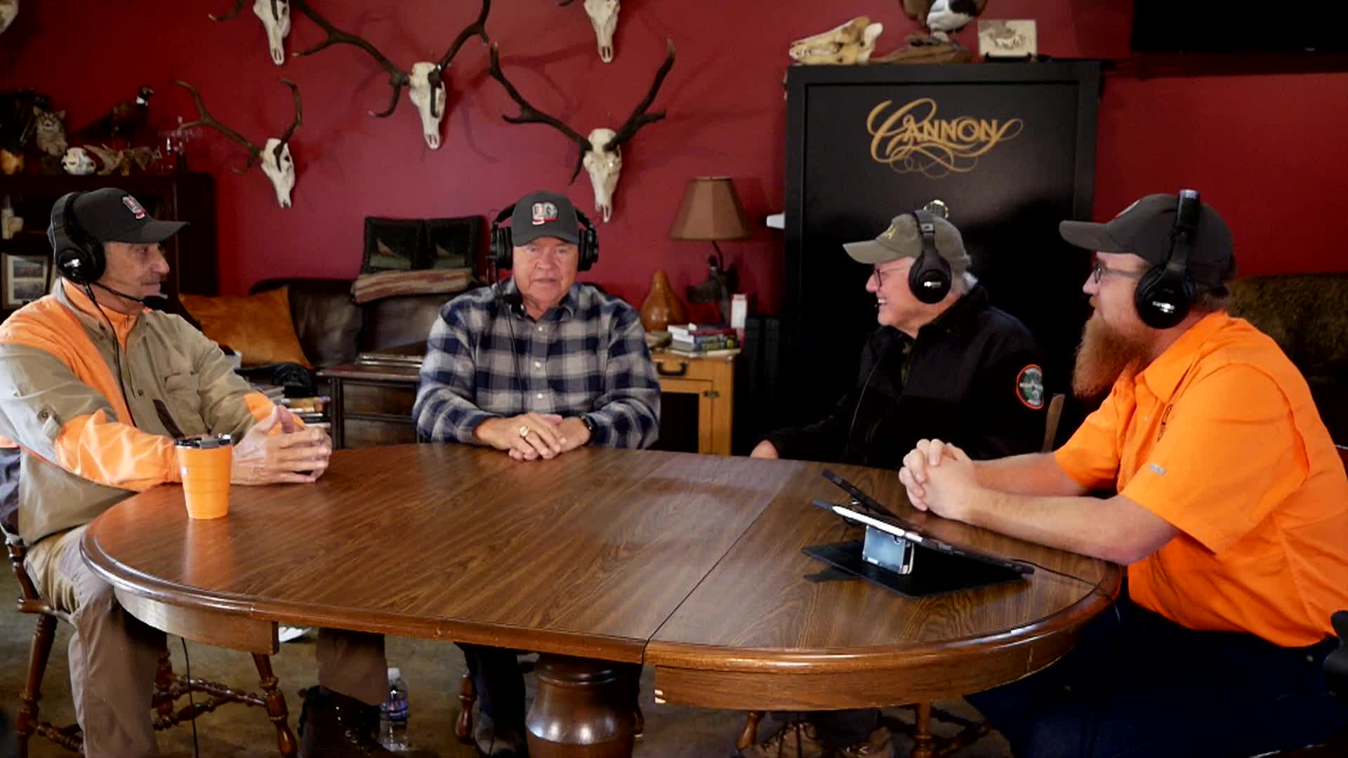 Two podcast hosts talking to two guests at a wooden table