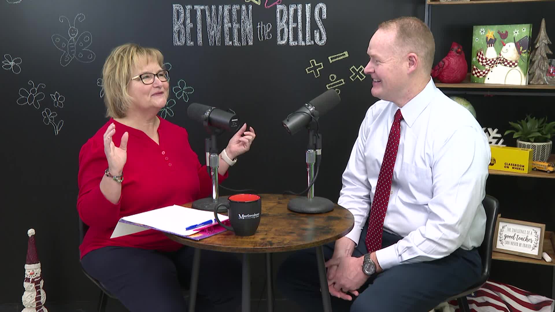 Man and woman at table talking into microphones