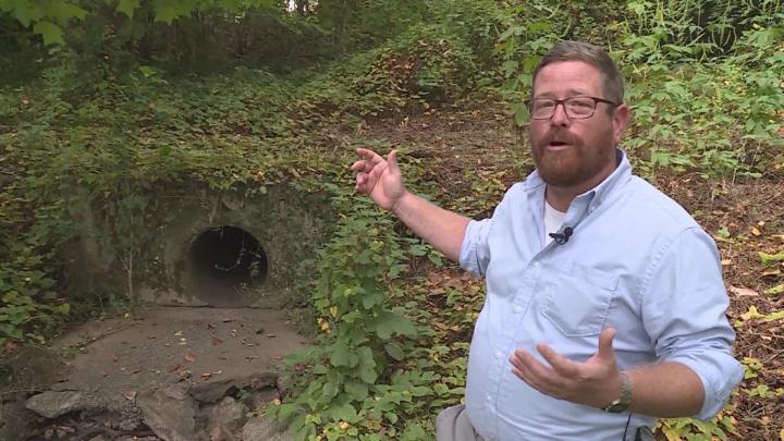 Man is standing and talking in front of drainage easement