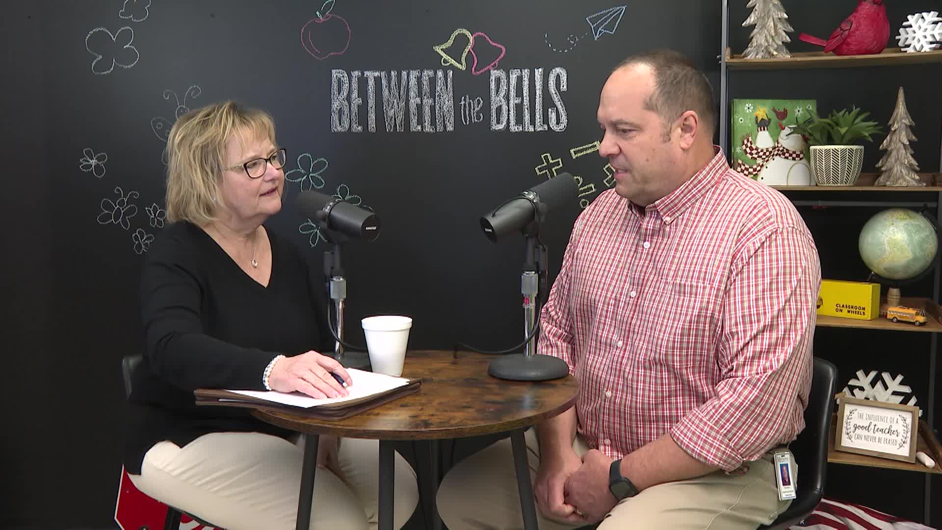 Woman and man sit at table and talk into mikes